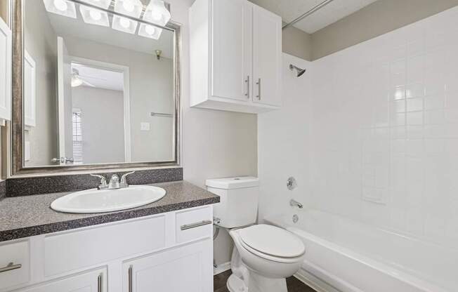 B1 bathroom with white walls, a sink, toilet, and bathtub at Jefferson Place Apartments in Irving, TX