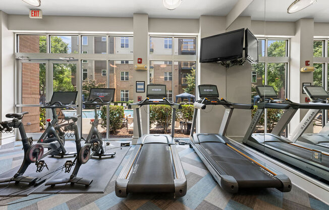 a gym with cardio equipment and windows at the apartments