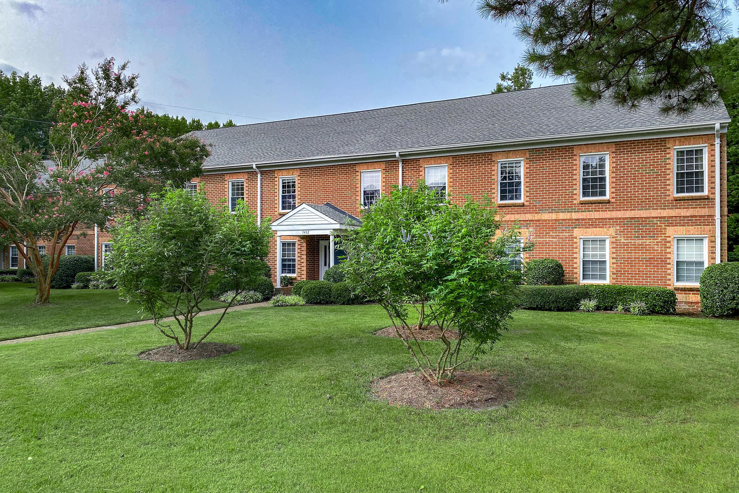 a house with a lawn in front of a brick building