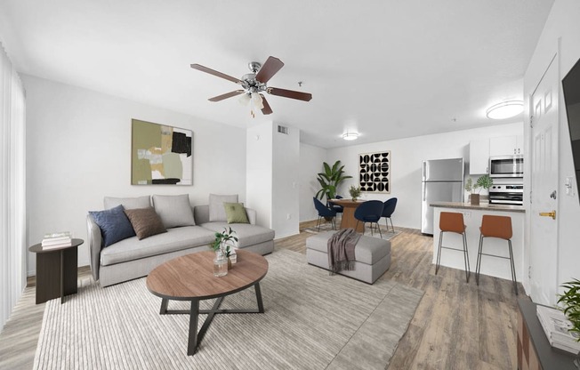 a living room with a couch table and chairs and a kitchen in the background