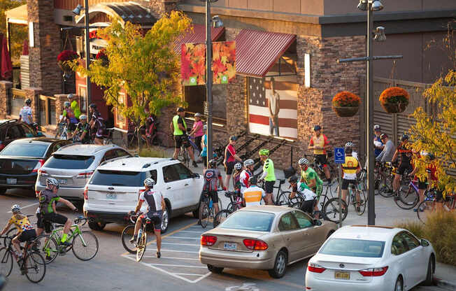 A group of cyclists are riding down a street in front of a building with a red awning.