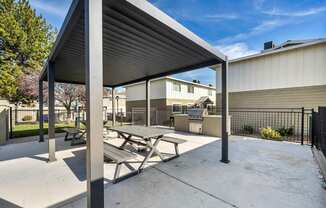 A concrete picnic area with a metal roof and benches.