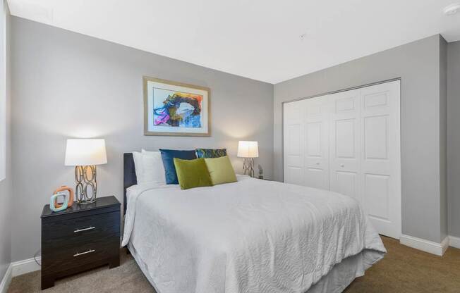 A bedroom with a bed, nightstands, and a painting on the wall.
