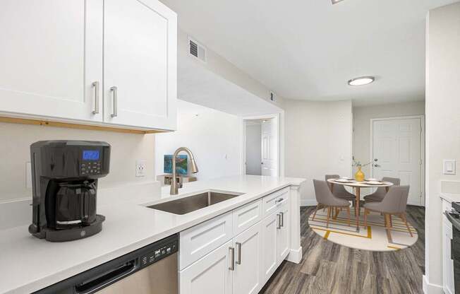 A kitchen with white cabinets and a black coffee maker.