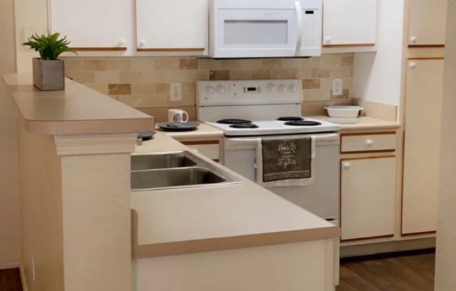 a kitchen with white cabinets and a white stove top oven at EDGEWOOD AT GABLES Apartments, Oklahoma, 74127