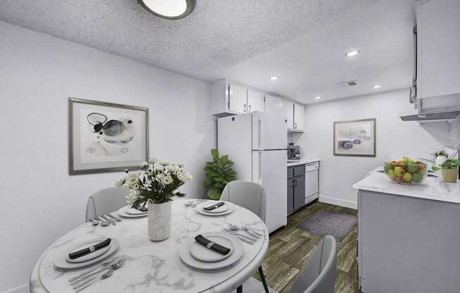 A dining room with a table set for two and a kitchen area in the background.