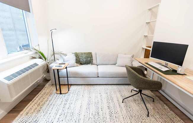 a living room with a couch and a desk and a tv