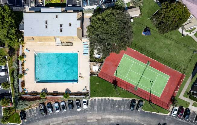 A tennis court is located next to a swimming pool.