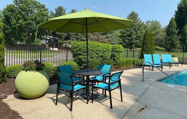 A green umbrella is above a table with chairs around it.