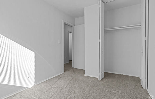 a bedroom with white walls and a door to a closet