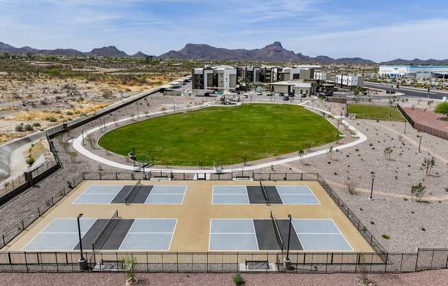 Tennis courts surrounded by a fence with a building in the background.