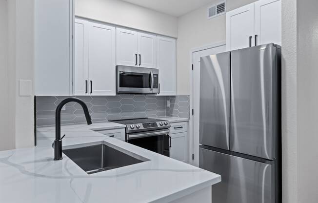 a kitchen with white cabinets and stainless steel appliances