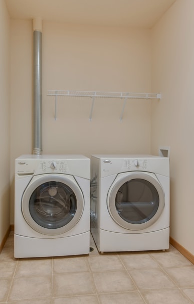 Two white front loading washing machines in a laundry room.