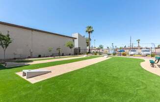 A park with a green lawn and a white wall.