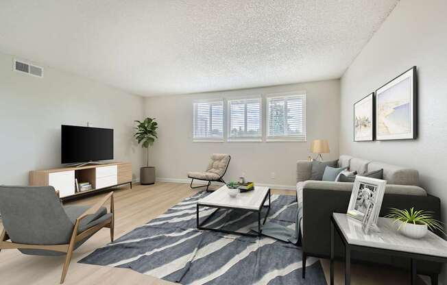 Pet-Friendly Apartments in Aurora, CO– Aurora Meadows – A living room with a grey couch, a chair, a coffee table, and a television.