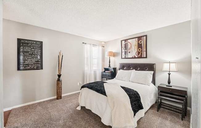 A bedroom with a bed, nightstand, and lamp.