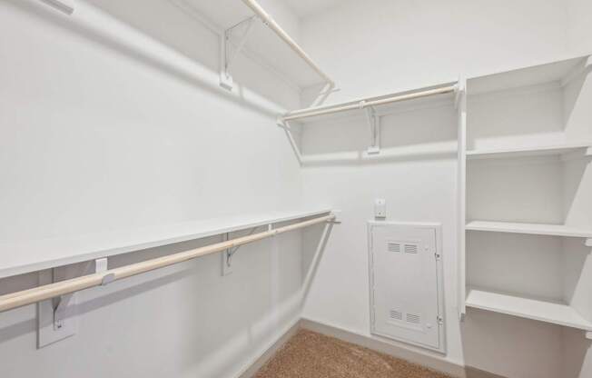 A white closet with shelves and a white electrical box on the wall.