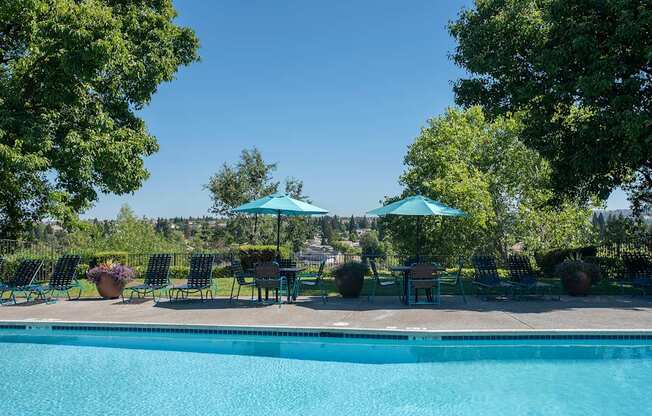 A pool surrounded by trees and chairs under umbrellas at Sunset Summit, Rocklin, CA, 95765