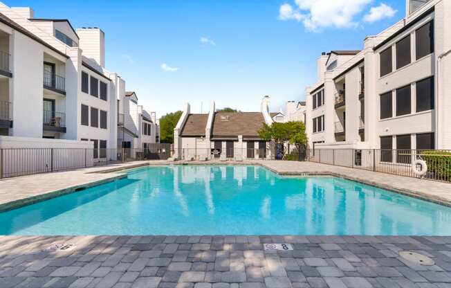 a swimming pool between two buildings with a blue sky in the background