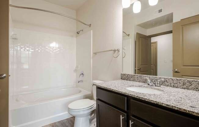 a bathroom with a toilet sink and bathtub at Parc at Bentonville Apartments in Bentonville, AR