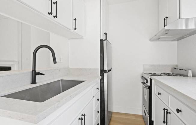 a kitchen with white cabinets and a sink and a refrigerator