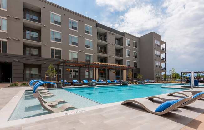 a swimming pool with chaise lounge chairs and a building in the background