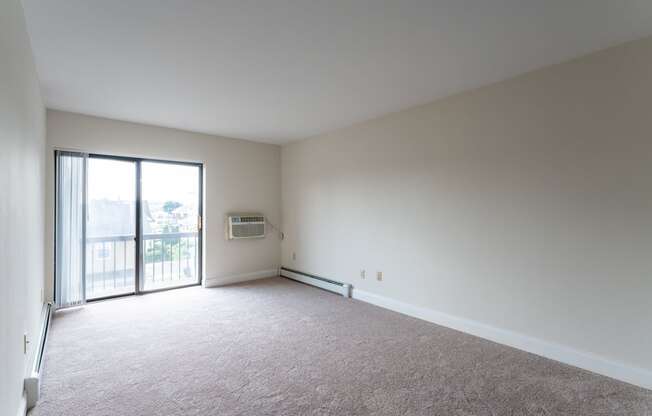 an empty living room with a sliding glass door to a balcony