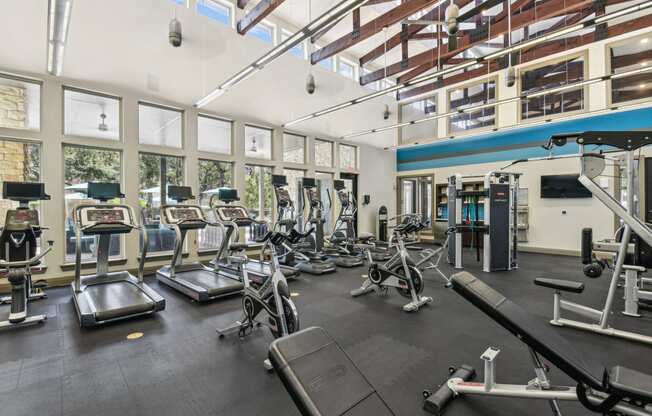 a gym with cardio equipment and windows in a building