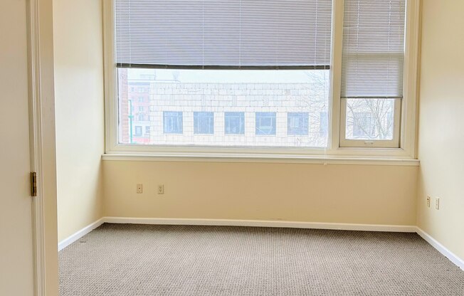 an empty room with a large window and a ceiling fan