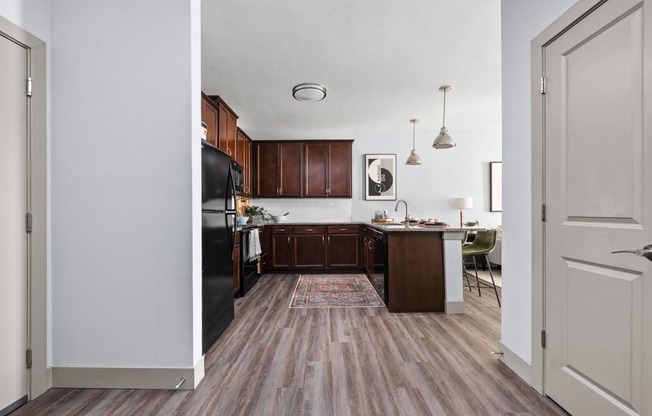 a kitchen with wood flooring and a black refrigerator at the Vue apartments in Indianapolis