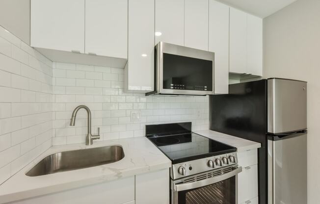 a kitchen with white cabinets and a sink and a refrigerator