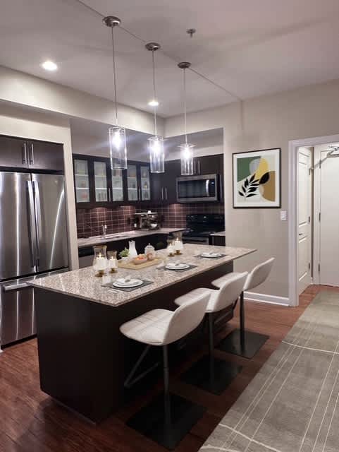 A modern kitchen with a large island and chairs.