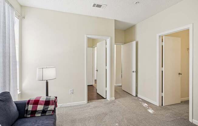 A living room with a grey couch and a lamp.