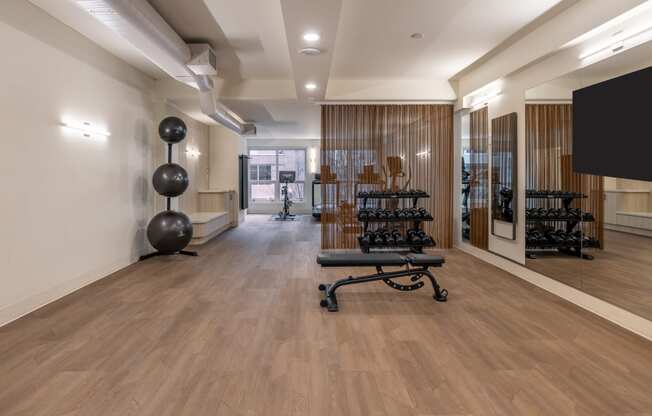a room with a chair and a tv in the corner and a wood flooring