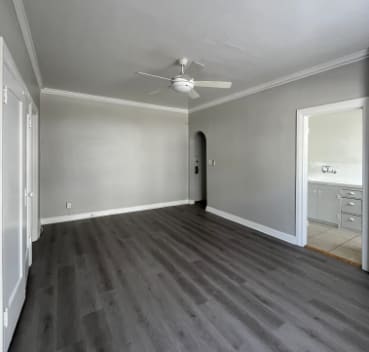 A room with a ceiling fan and wood flooring.