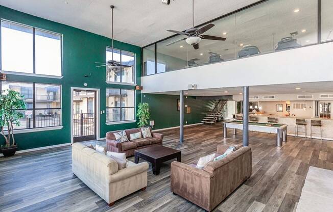 A living room with a green wall and a ceiling fan.