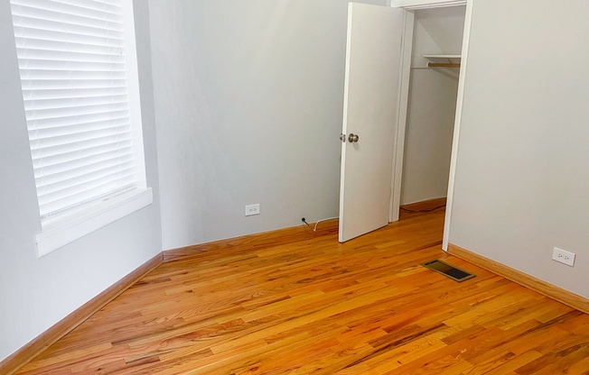 a bedroom with wood flooring and a door to a closet