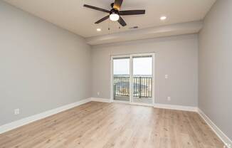 A room with a ceiling fan and sliding glass doors.