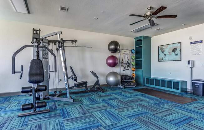 a home gym with exercise equipment and a ceiling fan