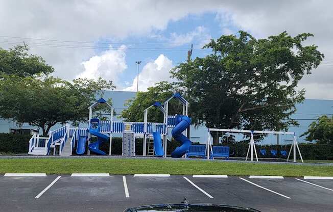 a playground with blue slides in a parking lot