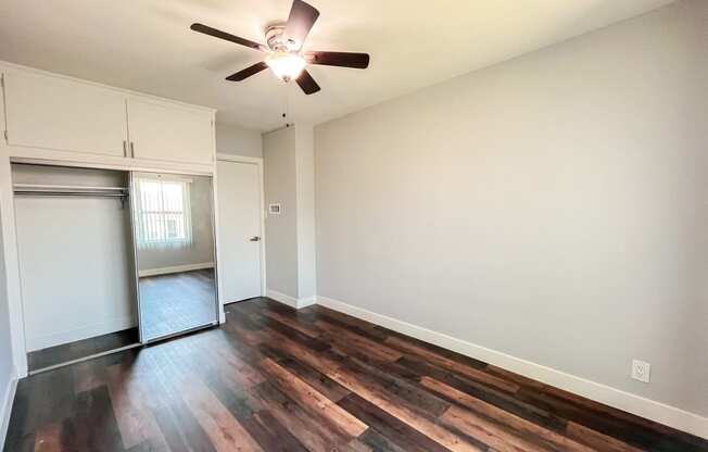 an empty living room with wood flooring and a ceiling fan