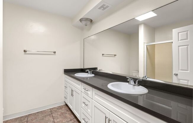 A bathroom with two sinks and a large mirror