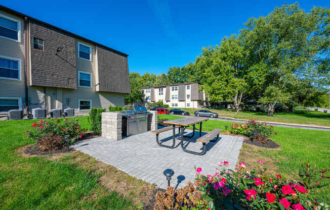 a patio with a picnic table and a grill in front of an apartment building