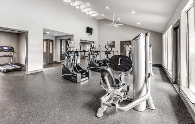 a gym with treadmills and other exercise equipment in a building with windows