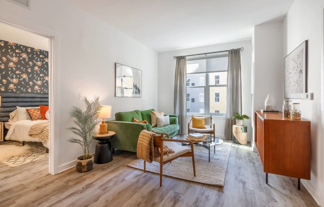 Model living room with a green couch and a large window