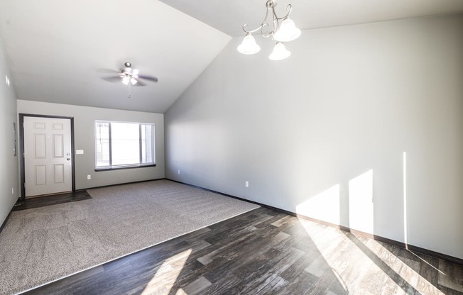 A spacious room with a ceiling fan and a door.