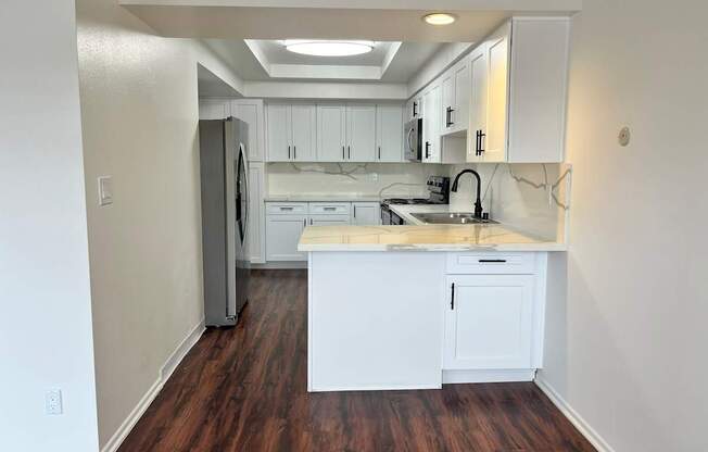 Dresden kitchen with white cabinets and a wooden floor.
