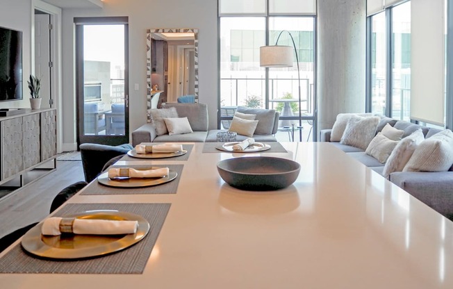 3-bedroom model view of kitchen island with the living room with couches and chairs in the background at The Hamilton apartments in Dallas, TX