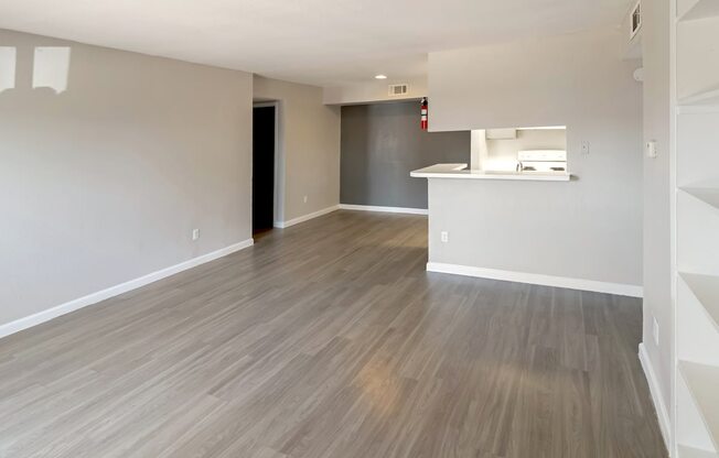 a spacious living room with built-in shelves and wood-style floors