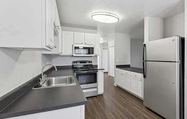 A modern kitchen with white cabinets and stainless steel appliances.